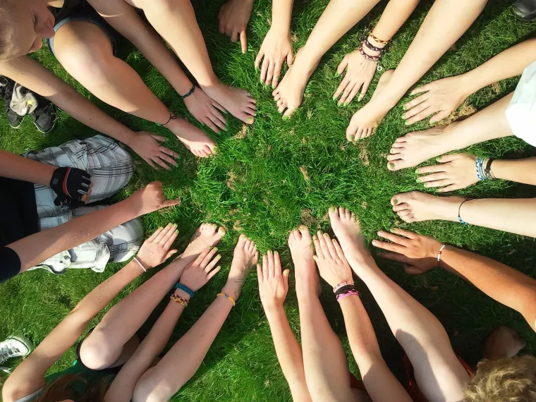 Photo of team's hands and feet in a circle on grass